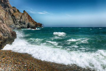 Fototapeta na wymiar Sea waves crashing on the shore and flowing above seashore pebbles