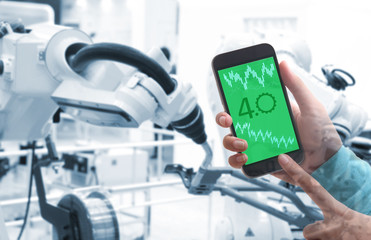 Man hand holding smartphone  with Augmented reality screen software and blue tone of automate wireless Robot arm in smart factory background, Industry 4.0 concept .