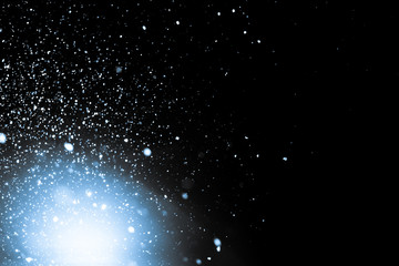 Many snowflakes on a black background with selective illumination lamp - blurred winter background, isolated