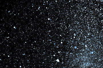 Many snowflakes on a black background with selective illumination lamp - blurred winter background, isolated