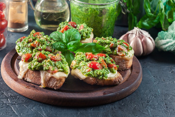 Bruschetta with fresh pesto, mozzarella and cherry tomatoes on cutting board