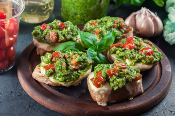 Bruschetta with fresh pesto, mozzarella and cherry tomatoes on cutting board