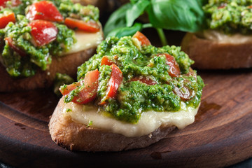 Bruschetta with fresh pesto, mozzarella and cherry tomatoes on cutting board