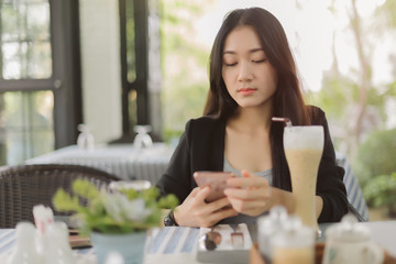 Portrait of asian woman use smartphone in coffee shop.  Business woman wait customer in resturant.
