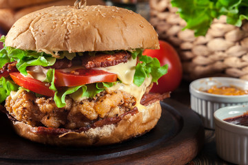 Delicious burger with chicken, bacon, tomato and cheese