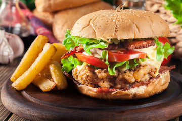 Delicious burger with chicken, bacon, tomato and cheese