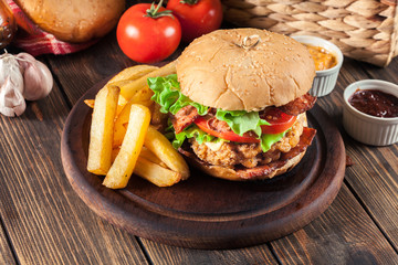 Delicious burger with chicken, bacon, tomato and cheese