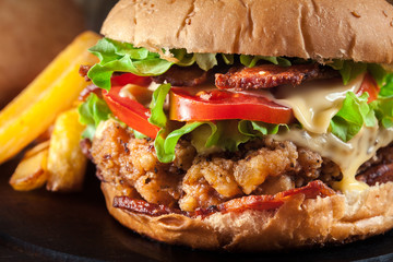 Delicious burger with chicken, bacon, tomato and cheese