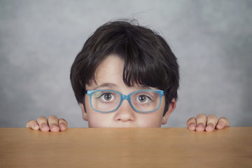 niño con gafas sobre una mesa de madera