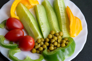Various vegetables on a plate - cucumbers, tomatoes, paprika and pea.