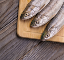 Fresh fish on the board. On a wooden background.