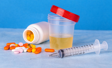 Urine container,  syringe and colored pills