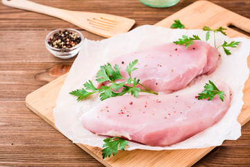 Raw turkey fillet in spices and herbs on a cutting board on a wooden table