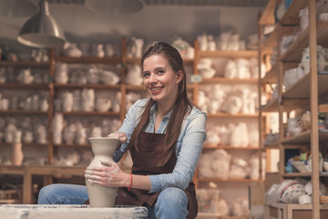 Smiling girl working on a potter's wheel