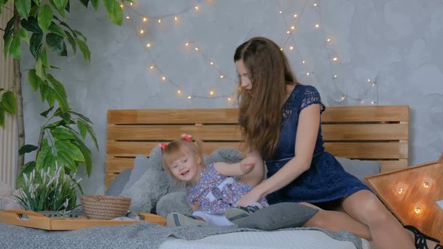 Young mother and her baby daughter playing togerher at home. Family, childhood and leisure concept