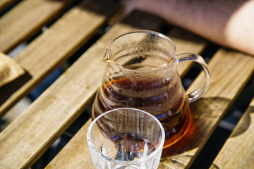 Glass pot with alternatively brewed coffee at the sunny street cafe on wooden table.