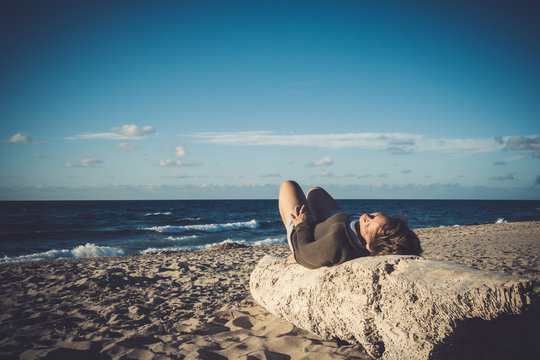 A woman lies on a log in Sardinia and enjoys the sun