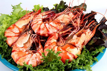 Grilled large fresh prawns  served with megetables on blue plate.