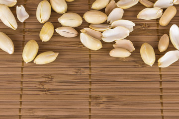 Peanut peeled roasted scattered on a bamboo napkin. Top view, close-up.
