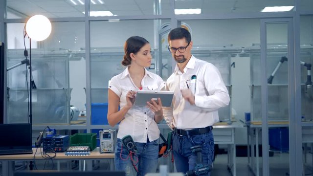 Female and male engineers are discussing something with a tablet computer