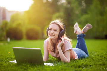 Girl in the Park working on a laptop with headphones