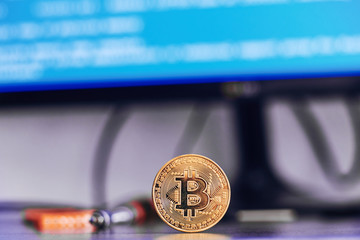 Bitcoin on a table with code on background