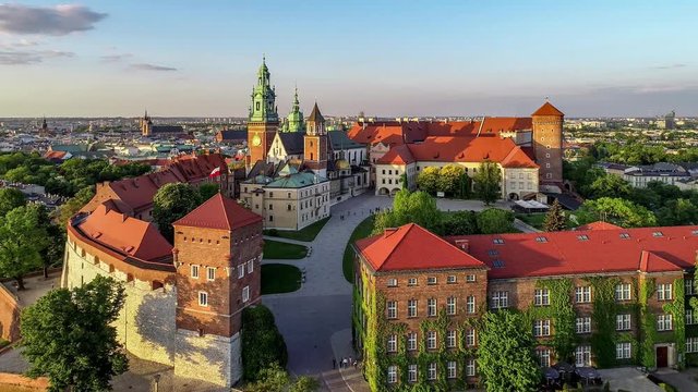 Royal Wawel Gothic Cathedral in Cracow, Poland, with Wawel castle, yard, park, tourists and Vistula river. Aerial 4K reveal video at sunset in spring. Old city with St. Mary church in the background