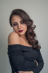 Naklejka premium Portrait of a charming brunette with beautiful curly hair in a black dress