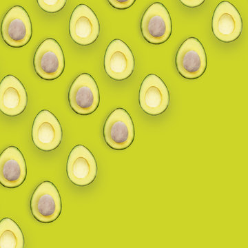 Avocado halves pattern isolated on green background, top view conceptual image with space for text.