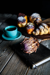 Croissant and white cup of black coffee on brown canvas.
