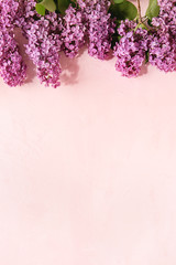 Spring purple lilac blooming branches over pink pastel background. Holiday or wedding greeting card. Copy space. Floral background. Toned image