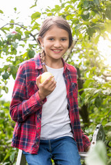 Portrait of beautiful smiling girl with appler posing in apple garden