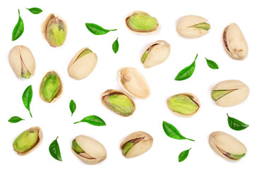 Pistachios decorated with green leaves isolated on white background, top view. Flat lay pattern
