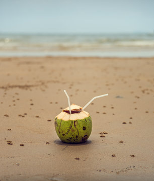 Coconut with a straw on the ocean. Tropical fruits.