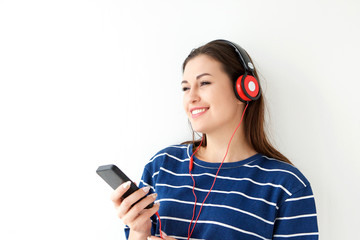 young woman listening to music with mobile phone and headphones against white background