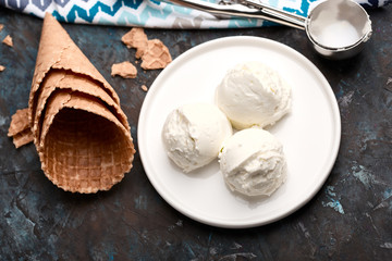 Ice cream balls, scoops and waffle cones on dark background. Advertising space.
