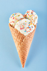 ice cream balls with colored sugar sprinkles in a Waffle Cone on a Blue Background. Vanilla ice cream in a waffle cone.
