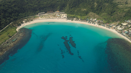 Aerial view of beautiful tropical beach with turquoise water in blue lagoon, Pagudpud, Philippines. Ocean coastline with sandy beach. Tropical landscape in Asia.