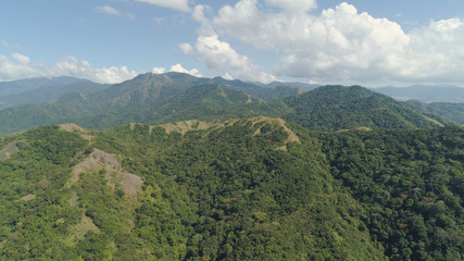 Aerial view of mountains covered with green forest, trees with blue sky. Slopes of mountains with tropical forest. Philippines, ,Luzon. Tropical landscape in Asia.