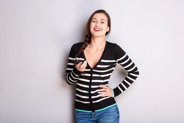 smiling girl holding mobile phone against gray background