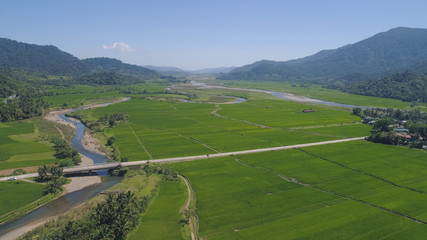 Mountain valley with river, farmland, rice fields. Aerial view of Mountains with green tropical rainforest, trees, jungle with blue sky. Philippines, Luzon.