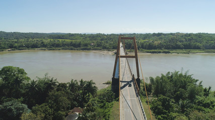 Fototapeta premium Aerial view of modern bridge with cars over tropical river in mountain province Philippines,Luzon.