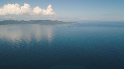 Aerial view of islands and coral reefs with turquoise water in blue lagoon, Philippines, Santa Ana. Seascape ocean coastline, mountains and blue sky with clouds. Tropical landscape in Asia.