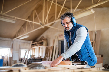 A man worker in the carpentry workshop, working with wood.