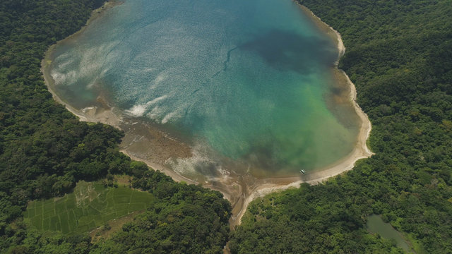 Aerial view of tropical beach in bay with turquoise water. Siwangag Cove. Coast of tropical island Palau with mountains covered rainforest. Santa Ana, province of Cagayan, Philippines.
