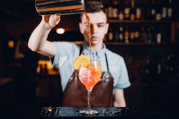 Close-up of barman mixes cocktail with ice orange, whiskey, liquor.