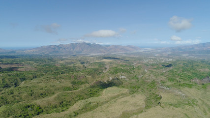 Aerial view of mountains covered with green vegetation, valley, trees in vicinity volcano Pinatubo. Slopes of mountains, sky and clouds. Cordillera region. Luzon, Philippines.