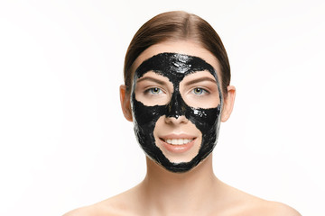 Young beautiful woman applying a mask for the face of the therapeutic black mud. Spa treatment