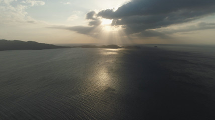 Aerial view of coast of the island at sunset, sunshine with glare on surface water at sunset. .Anilao, Caban Island. Orange sunset over the sea. Philippines, Luzon. Travel concept.