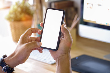 close-up man hand holding mobile phone showing blank screen and finger touching on work table.